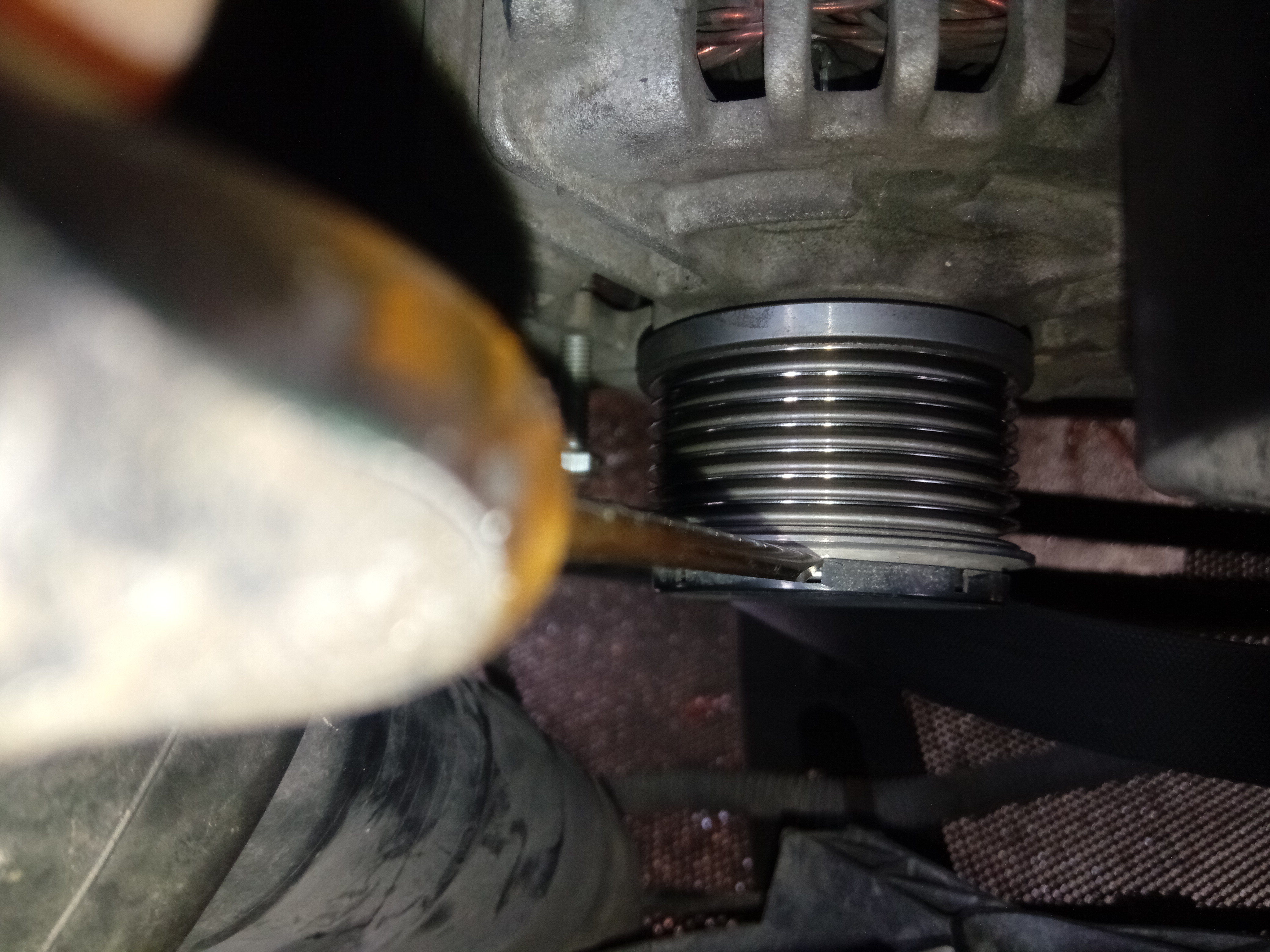 用螺丝刀撬开发电机单向轮上面的塑料盖板。