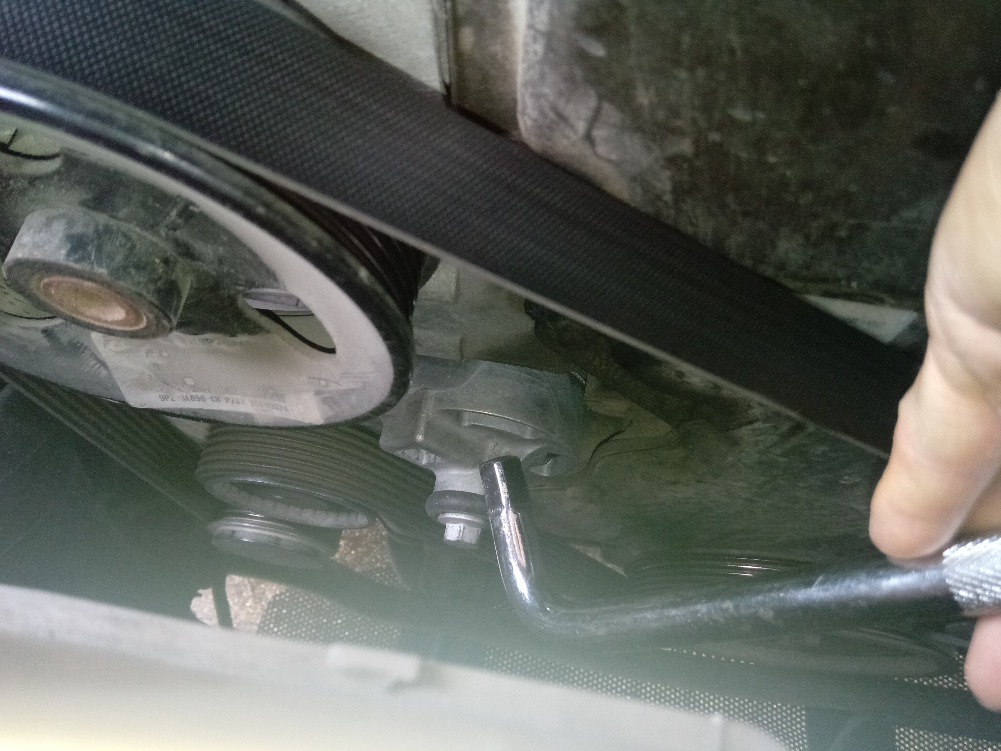 用工具插进涨紧轮的孔，扳动涨紧轮，松开并取下皮带。